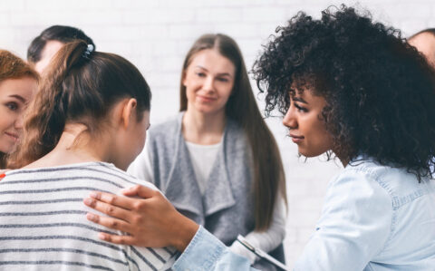 Support group patients comforting woman at therapy session