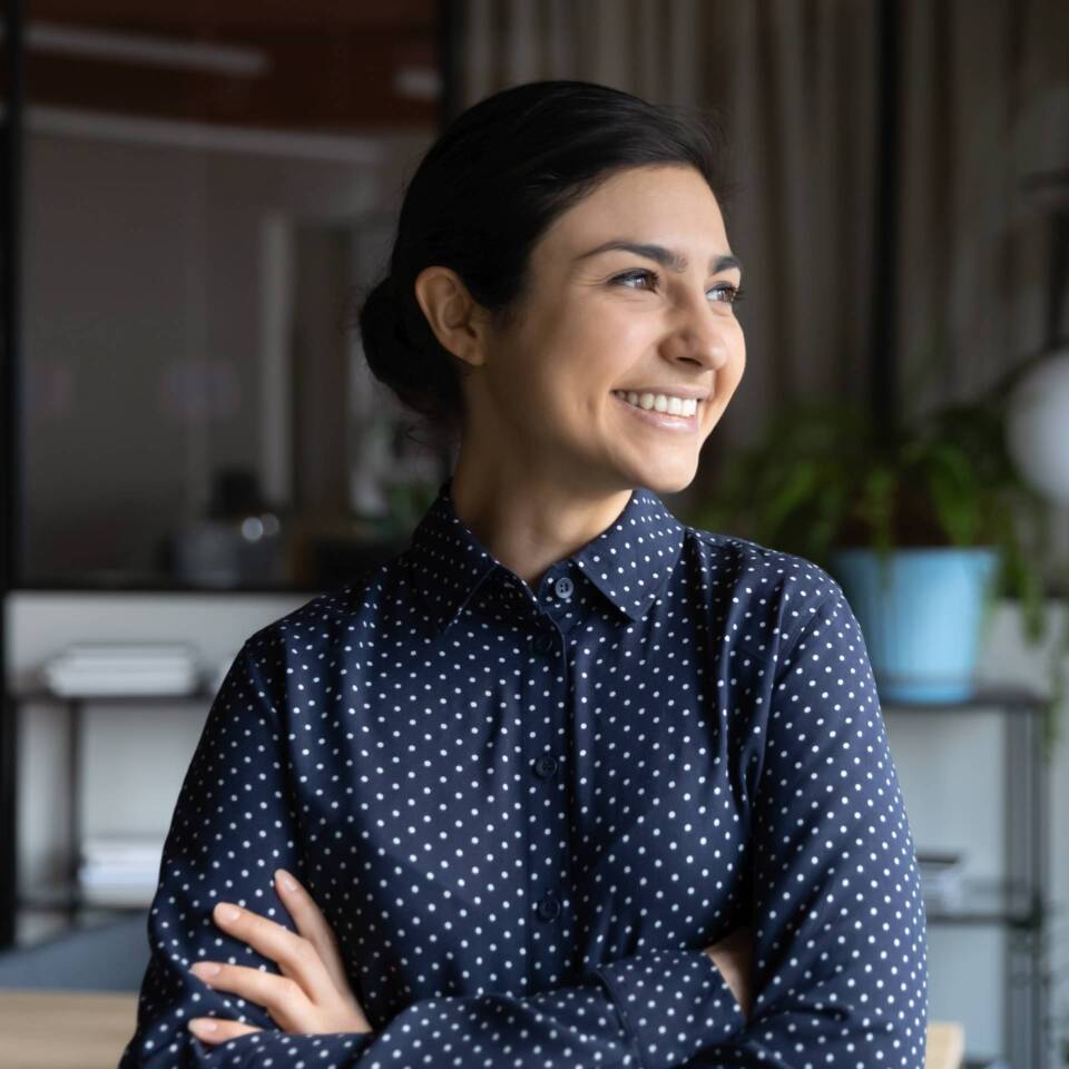 Indian businesswoman looking out the window feels proud by achievements
