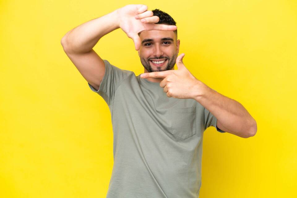 Young Arab handsome man isolated on yellow background focusing face. Framing symbol